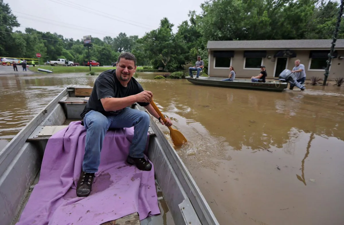 A man uses a boat to look around Lakeside Manor mobile home park after flash flooding took over the area on July 2, 2015. (Huy Mach/St. Louis Post-Dispatch via AP)