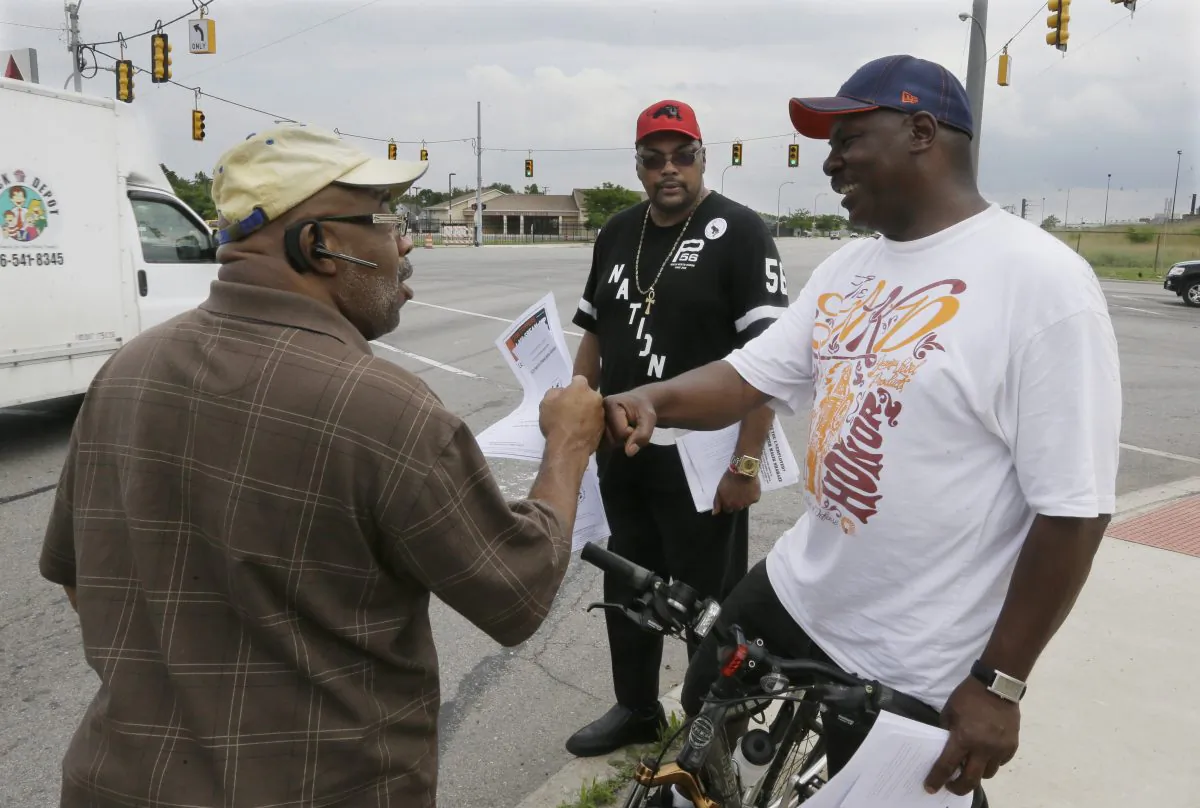 In this photo taken June 15, 2015, Chris Samuel, left, gets a fist bump from supporter Milton Stanciel after talking about rising crime in Detroit. (AP Photo/Carlos Osorio)