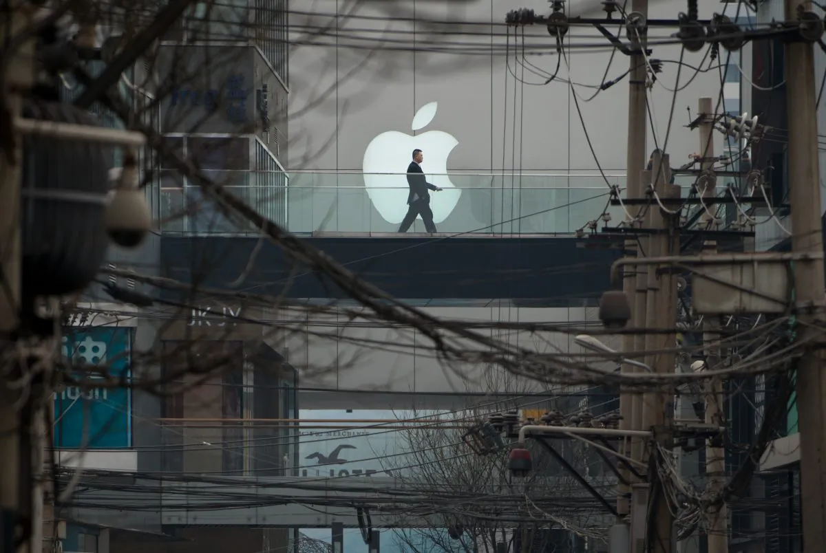 A man walks past an Apple logo displayed above a street at a shopping mall in Beijing on March 29, 2013. (Ed Jones/AFP/Getty Images)