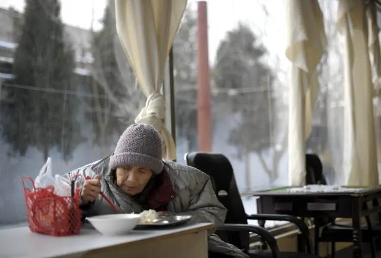 An elderly woman is eating a meal in a nursing home. China's one-child policy and aging heighten the shortage of elder care. (Liu Jin/AFP/Getty Images)