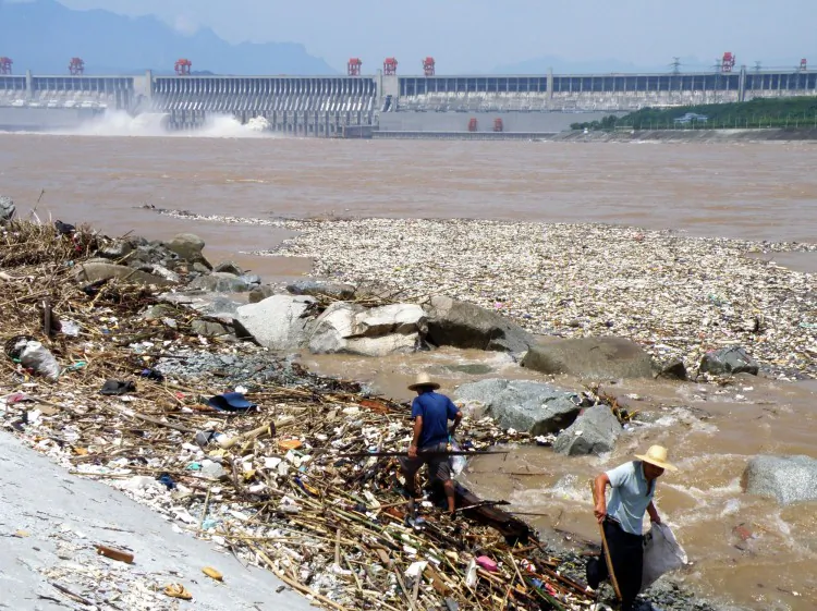 Two workers clean up trash along the bank of the Yangtze River near the Three Gorges Dam in Yichang, in central China's Hubei province on Aug. 1, 2010. (STR/AFP/Getty Images)