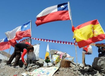 A relative of one of the 33 miners trapped in the San Jose mine, places a Spanish flag given by Spanish tourists beside several Chilean ones, near Copiapo, 800 km north of Santiago, September 13. (Ariel Marinkovic/Getty IMages)