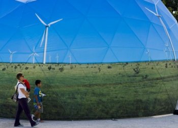 A family passes by one of the stands promoting green energy at the Climate Village in Cancun, Mexico, on Dec. 4. (Omar Torres/AFP/Getty Images)