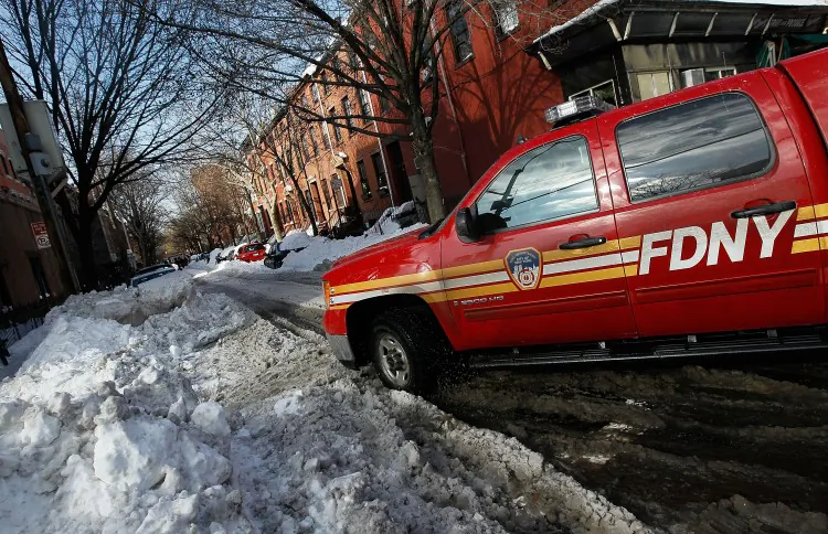 A fire department vehicle stands by as bystanders and emergency workers attempt to free a stuck ambulance on a side street in the Boerum Hill neighborhood of Brooklyn December 29, 2010 in New York City. Many side streets, especially those in the outer boroughs, are still unplowed in the wake of a massive snowstorm that crippled much of New York and left millions of holiday travelers stuck at airports and train stations around the eastern seaboard. (Chris Hondros/Getty Images)