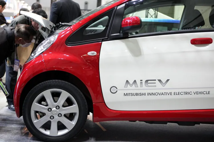 Visitors look at Mitsubishi Motors Corp.’s electric vehicle i-MiEV displayed during Automotive World 2011 last year in Tokyo. The i-MiEV is set to be the least expensive all-electric car in the United States when it is rolled out nationwide this summer. (Kiyoshi Ota/Getty Images)