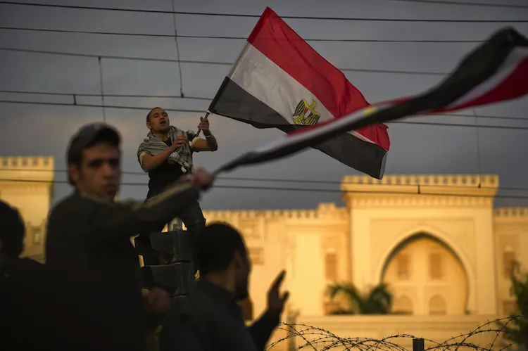 An Egyptian waves his national flag as demonstrators gather outside the Presidential Palace in Cairo on Feb. 11, 2011. (Pedro Ugarte/AFP/Getty Images)