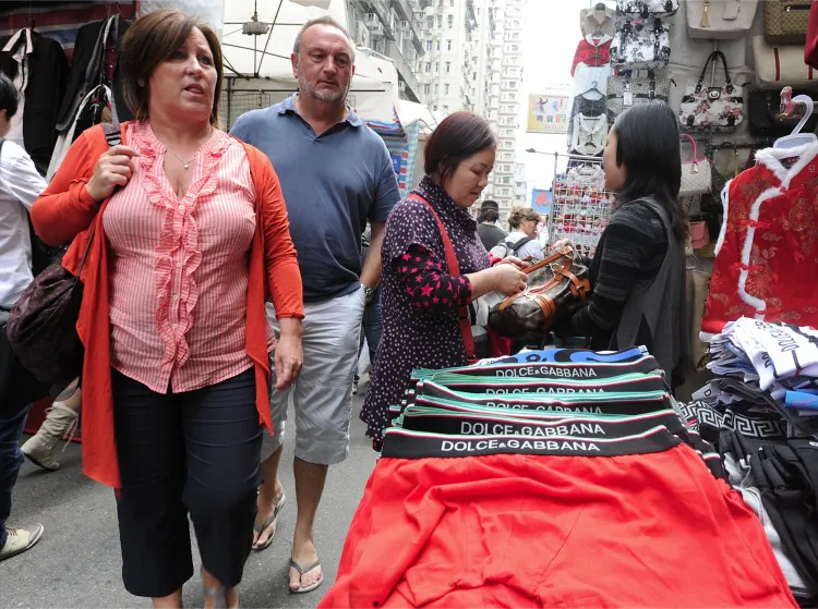 Shoppers walk past stalls at the 'ladies market' in Hong Kong, March 2. The open-air shopping magnet for tourists is listed on the U.S. Trade Representative’s 'Notorious Markets List' for counterfeit and pirated goods. (MIKE CLARKE/AFP/Getty Images)