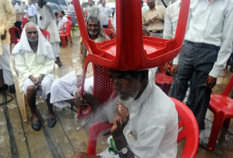A farmer smokes a cigarette whilst sheltering from the rain under a chair in a political rally few years ago. The Indian government enacted tobacco ban in 2003 that makes smoking in public places an offense. (PRAKASH SINGH/ Getty Images)