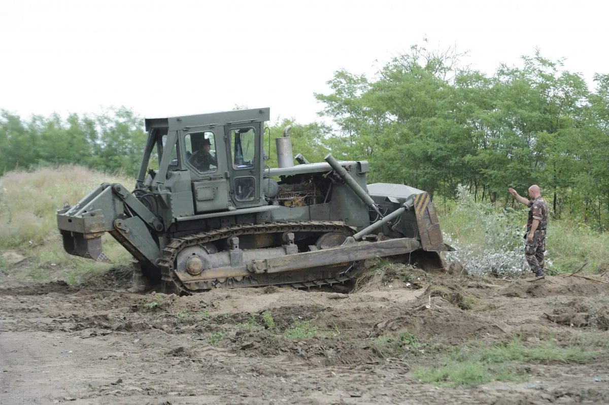 A bulldozer of the Hungarian Defence Force is used to prepare the terrain for the building of at the Hungarian-Serbian border near Morahalom, 179 kms southeast from Budapest, Monday, July 13, 2015. The fence is meant to stem the unprecedented flow of migrants, the government said Monday. (Zoltan Gergely Kelemen/MTI via AP)