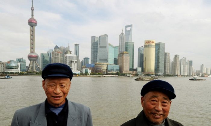Two Chinese farmers from Henan Province pose for photos in front of the Pudong Financial district skyline from the historic Bund in Shanghai on Oct. 31, 2011. The income gap in China is close to the UN’s warning level for social unrest, according to a recent survey. (Mark Ralston/AFP/Getty Images)