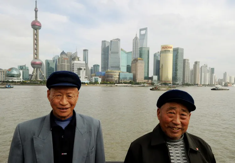 Two Chinese farmers from Henan Province pose for photos in front of the Pudong Financial district skyline from the historic Bund in Shanghai on Oct. 31, 2011. The income gap in China is close to the UN’s warning level for social unrest, according to a recent survey. (Mark Ralston/AFP/Getty Images)