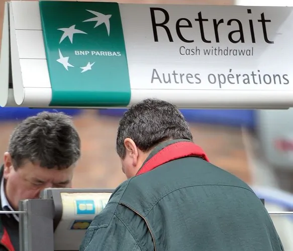 A man withdraws cash from an ATM at French bank BNP Paribas in Bailleul, Northern France, on Nov. 3. Credit ratings agency Moody's downgraded the debt ratings of France's three biggest banks. (Philippe Huguen/AFP/Getty Images)
