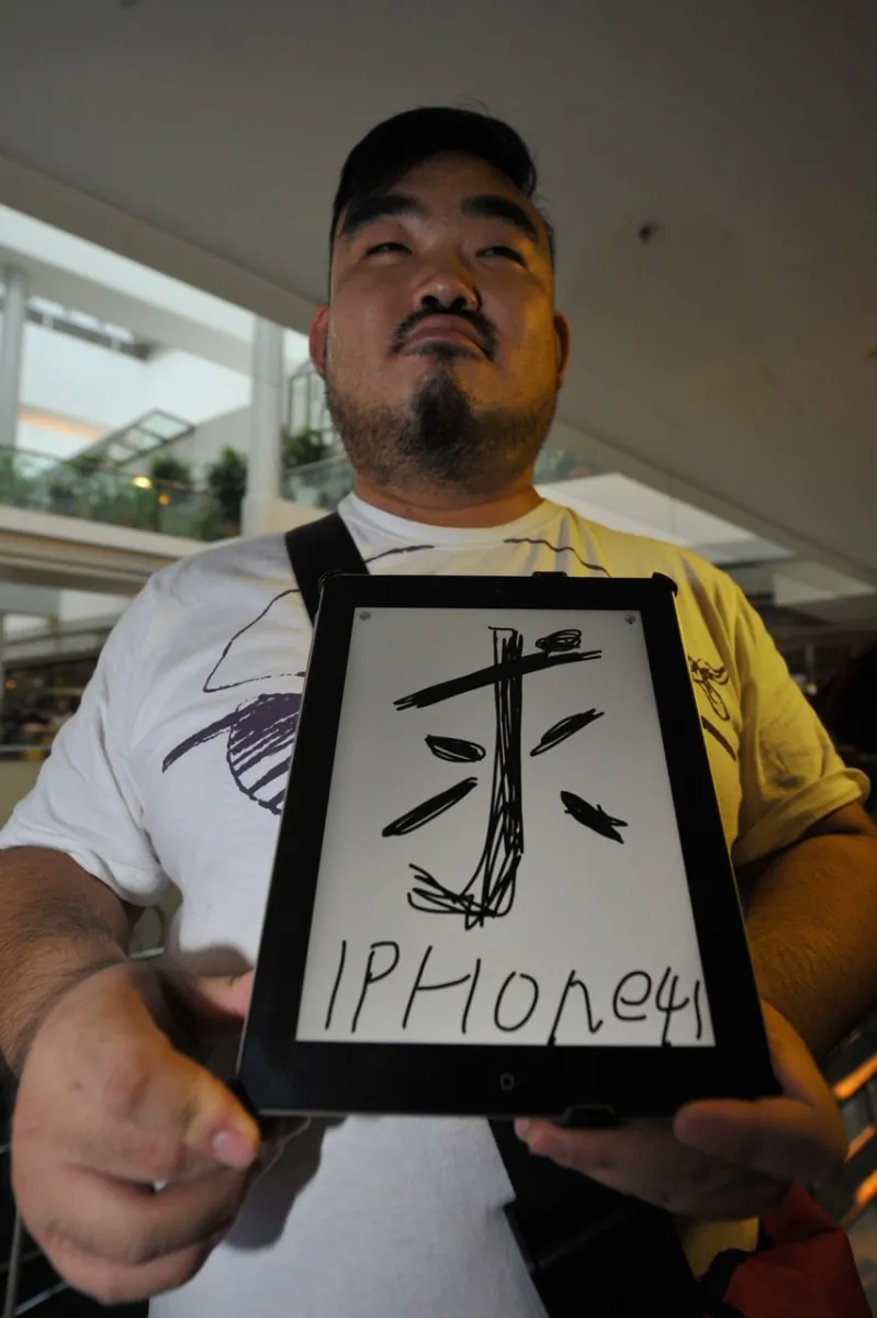 Bob Wong, 26, a designer from Shenzhen, China, holds an iPad that reads, “Want iPhone 4S” near the Hong Kong Apple Store on Nov. 11, 2011. (Aaron Tam/AFP/Getty Images)
