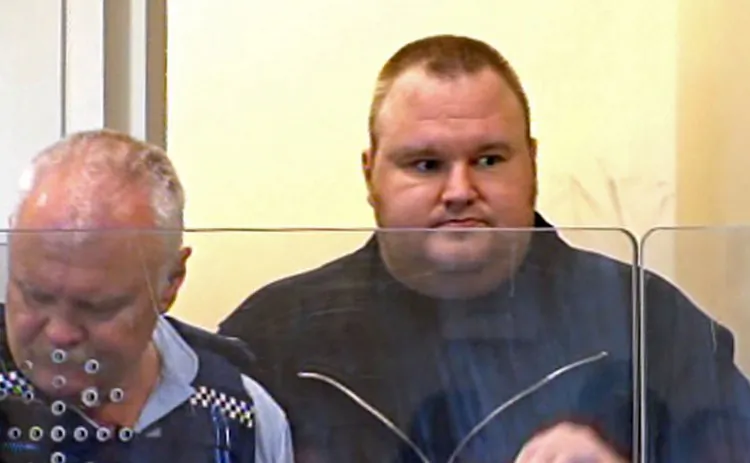 Internet guru and founder of Megaupload.com, Kim Schmitz, also known as "Kim Dotcom," was escorted by a policeman as he appeared in an Auckland district court in New Zealand on January 20, 2012. (STR/AFP/Getty Images)