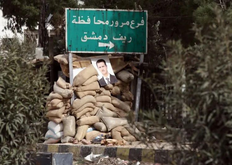 A picture of Syrian President Bashar Assad hangs on unused sand bags placed by the Syrian amry close to the city of Harasta north of Damascus on February 15, 2012. (Photo credit should read Louai Beshara/AFP/Getty Images)