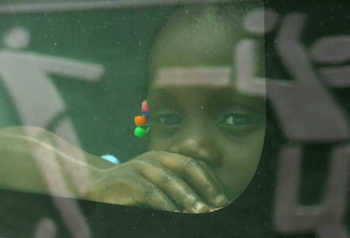 In this June 29, 2015 photo, a girl born in the Dominican Republic to Haitian parents peers through the window of a government car that will transport her and her family to the border with Haiti, in Santo Domingo, as her family returns voluntarily to their native Haiti after living in the DR several years. (AP Photo/Ezequiel Abiu Lopez)