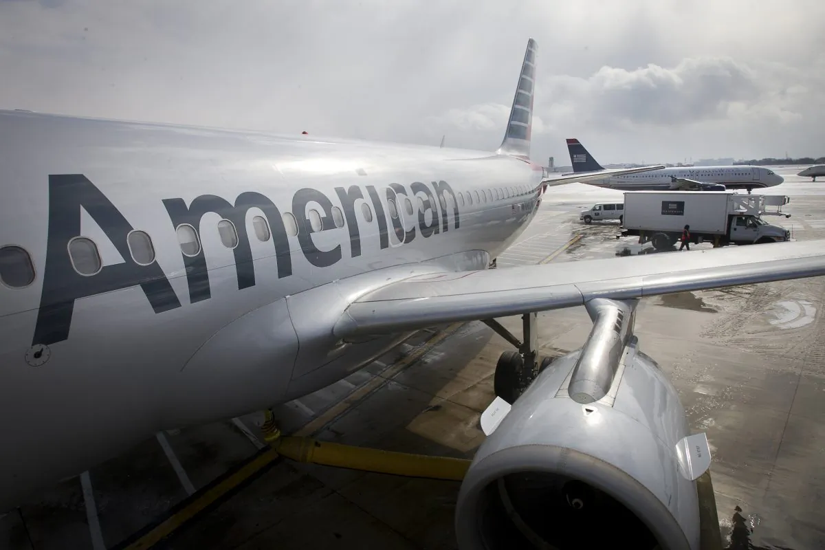 In this Feb. 26, 2014 file photo, an American Airlines Airbus A319 is parked at a gate at Philadelphia International Airport as a US Airways plane taxis in the background, in Exton, Pa. (Alejandro A. Alvarez/Philadelphia Daily News via AP)