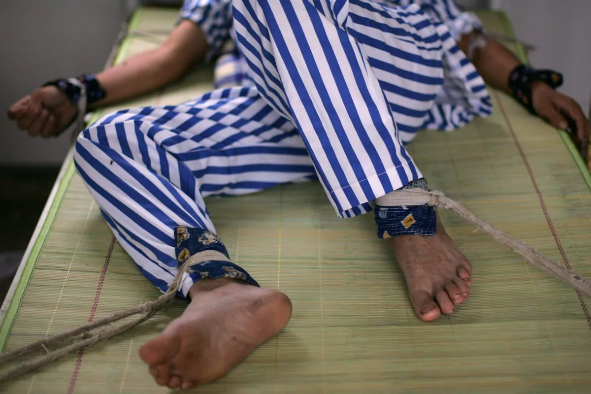 A mental patient lies in bed with arms and legs being bound at the Anxian Mental Hospital, in Sichuan Province, China, on Aug. 24, 2008. Beginning in 2000, the Chinese regime began the widespread use of mental hospitals to detain and punish dissidents. (China Photos/Getty Images)