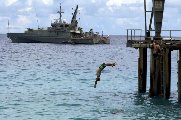 Off duty Australian Navy personnel enjoy some relaxation diving into the Indian ocean near by a Australian Navy boat used to intercept asylum seekers, docked at the Flying Fish Cove, Christmas Island, Australia.