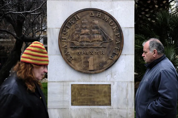 People walk past a monument featuring a replica of the last edition of the Greek currency, the drachma, in the center of Athens in February. If Greek voters decide to leave the euro currency, it would mean a return to the drachma. (ARIS MESSINIS/AFP/Getty Images)