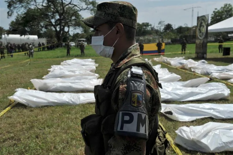 A military police officer stands guard at the Apiay air base in Colombia next to the corpses of FARC guerrillas killed in a joint operation by the Colombian army, air force and police on March 27. (Guillermo Legaria /AFP/Getty Images)