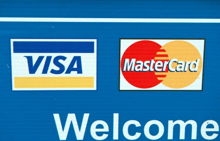 Visa and MasterCard credit card logos are seen on a sign in Washington on March 30, 2012. Starting Jan. 27, merchants have the ability to charge a checkout fee for customers using such credit cards. (Nicholas Kamm/AFP/Getty Images)