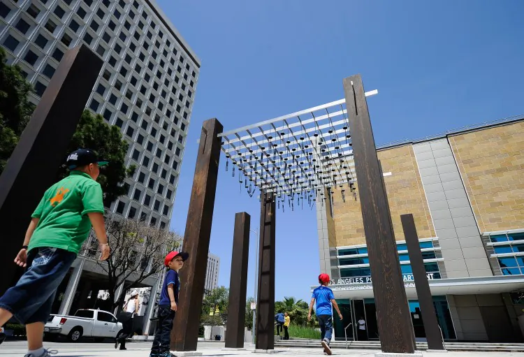 Children walk under an art installation outside the new LAPD Metropolitan Detention Center. Built at the site where a parking kiosk was burned in front of LAPD's Parker Center during the 1992 Los Angeles riots, the installation features more than 100 dangling metal bells, with words like 'Freedom' and 'Justice' suspended in the breeze. (Kevork Djansezian/Getty Images)