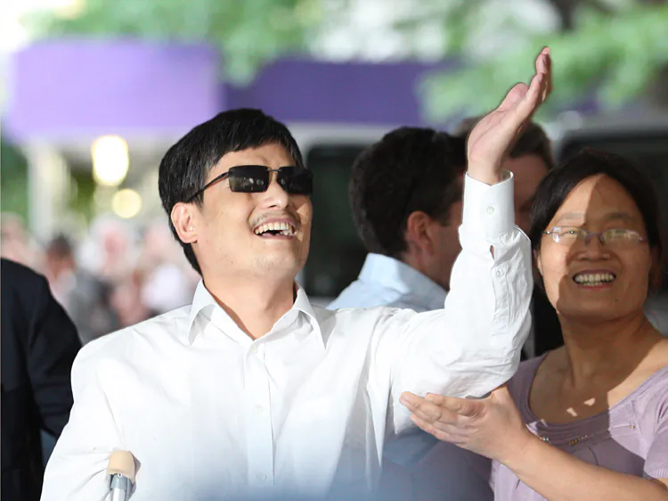 Chen Guangcheng gestures beside his wife Yuan Weijing before making remarks to the media, upon his arrival at New York University campus on May 19. (Andy Jacobsohn/Getty Images)