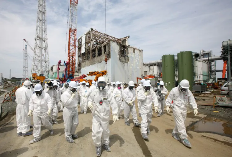 Members of the media and Tokyo Electric Power Co. (Tepco) employees look at the No. 4 reactor building (rear), amongst tsunamai damage, at the company's Fukushima Daiichi nuclear power plant in Okuma Town, Fukushima Prefecture on May 26, 2012. (Tomohiro Ohsumi/AFP/GettyImages)