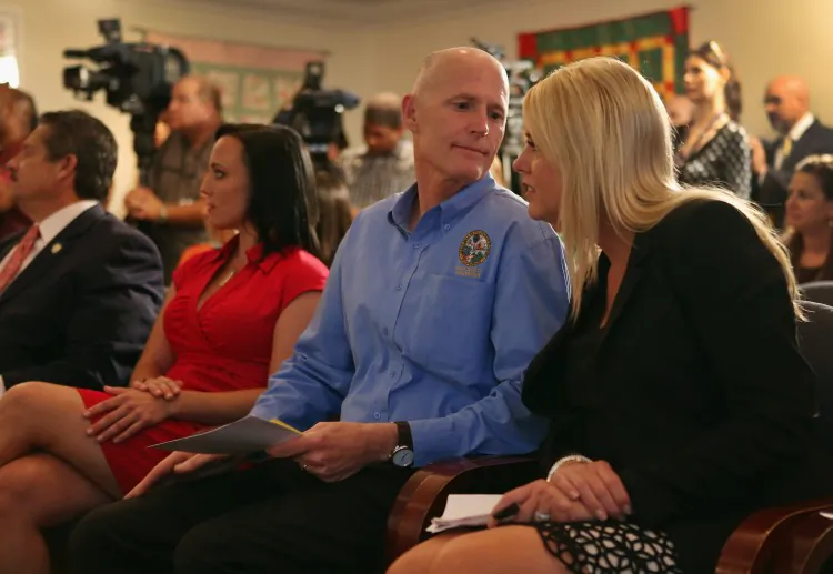 Florida Gov. Rick Scott speaks with Attorney General Pam Bondi during a bill signing ceremony at the Kristi House on June 12 in Miami, Fla. The governor is in a legal battle with the U.S. Justice Department over the state’s effort to remove noncitizens from lists of registered voters ahead of this year’s presidential election. (Joe Raedle/Getty Images)