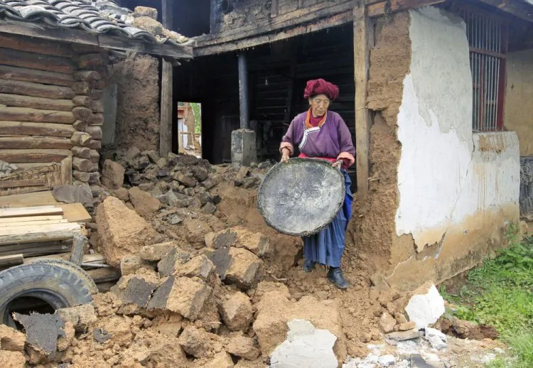 A villager walks amongst rubble outside her earthquake damaged home in southwest China's Yunnan province. (STR/AFP/Getty Images)