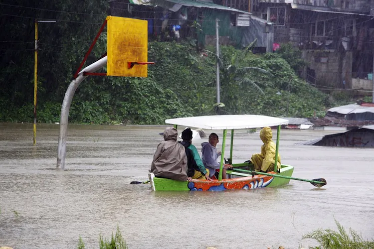 Residents affected by floodings, ride on a boat as they survey their houses in Camp Lagoon in Baguio, Trinidad province, north of Manila on August 15, 2012, as tropical Storm Kai-tak hit the northeast of the main island of Luzon before dawn. ( JJLandingin/AFP/Getty Images)