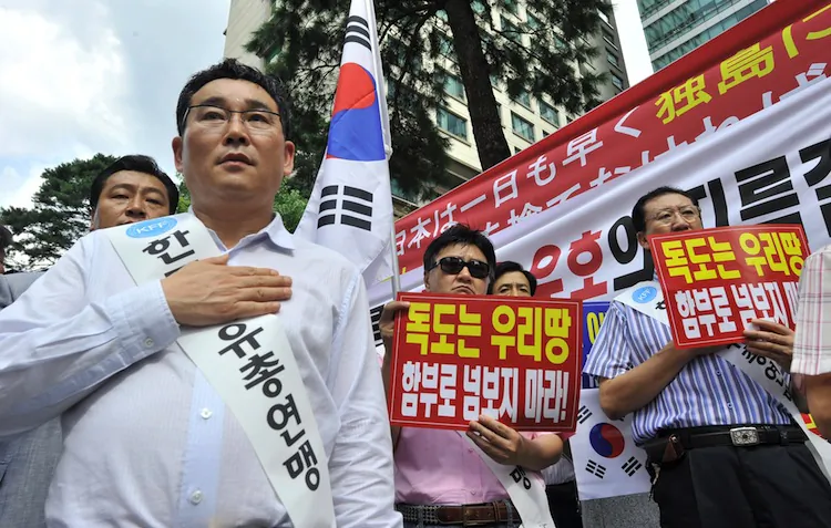South Korean protestors salute the national flags during a rally in front of the Japanese embassy in Seoul on August 17, 2012 denouncing Japan's claims to the tiny chain of Seoul-controlled rocky islands, known as Dokdo in Korea and Takeshima in Japan. (Jung yeon-Je/AFP/Getty Images)