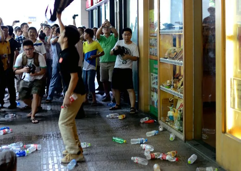 A group of protesters pelt a Japanese restaurant (R) with plastic bottles as they attend a rally against Japan's claim of islands known as Senkaku in Japan and Diaoyu in China, in Hangzhou in China's Zhejiang province on August 19, 2012. (STR/AFP/GettyImages)