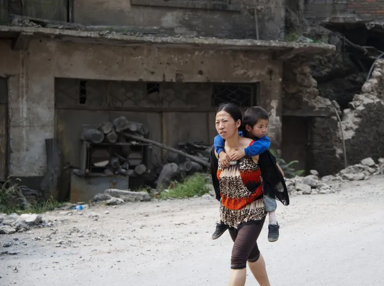 This photo taken on Sept. 8, 2012 shows a woman carrying her child on her back along a street in Yiliang after two quakes hit the area on the border of southwestern Yunnan and Guizhou provinces an hour apart around the middle of the day followed by a string of aftershocks. (STR/AFP/GettyImages)