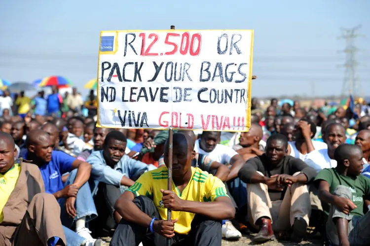 Striking Lonmin platinum mine workers sit on Sept. 14, 2012 in Marikana, South Africa, listening to their union representatives reporting back from a meeting with the management. (Alexander Joe/AFP/Getty Images)