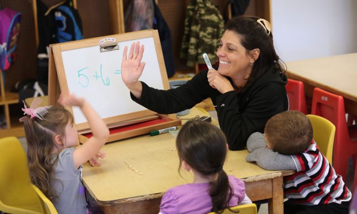 A teacher congratulates a child during a math lesson at the Head Start school in Woodbourne, N.Y., in September. New York is one of five states testing a new program to increase school hours and boost student achievement. (John Moore/Getty Images)