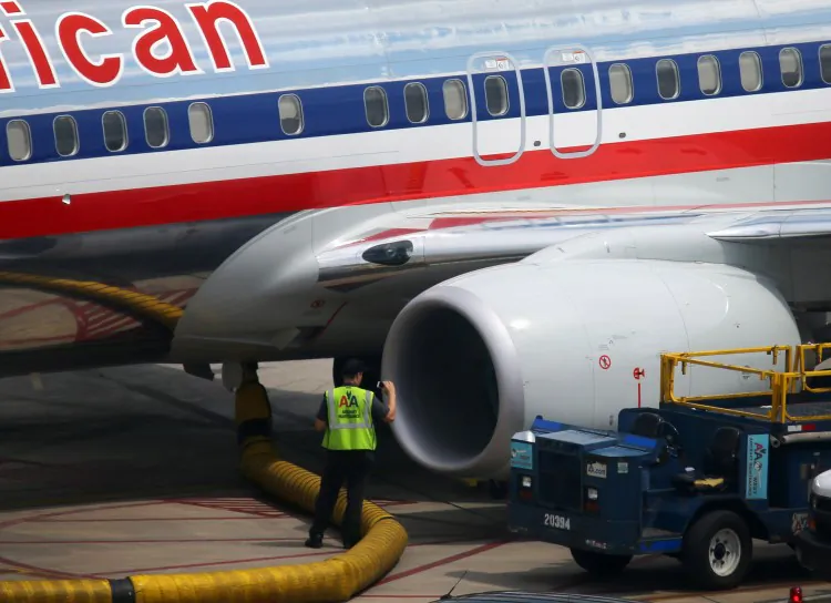 A worker stands next to an American Airlines plane at the Miami International Airport on Sept. 25. American Airlines is threatening to sue its pilots for what it says are frivolous maintenance requests and other tactics meant to delay flights. (Joe Raedle/Getty Images)
