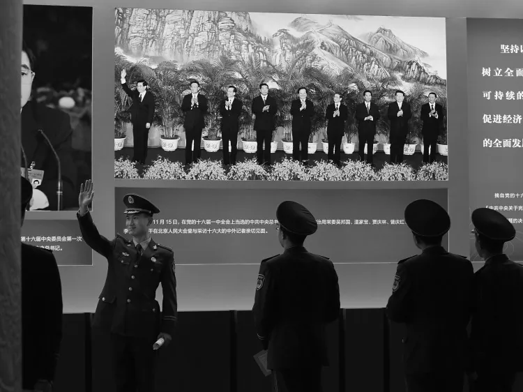 A paramilitary policeman poses for photo in front of the photo of Hu Jintao while visiting an exhibition, on Oct. 30, 2012, in Beijing. A source said that membership of the Politburo, the most powerful policy-making body in China, may reduce its membership from 25 to 22 and the Standing Committee’s membership will be reduced from nine to seven. (Feng Li/Getty Images)