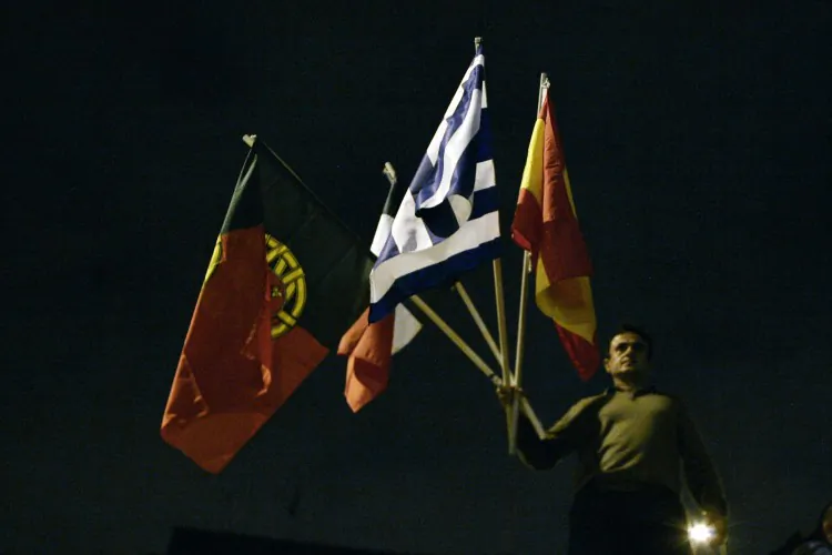 A protester holds up the national flags of the "PIGS" countries (an acronym for the economies of Portugal, Italy, Greece, and Spain) outside the Greek parliament on Nov. 7 in Athens, Greece. (Milo Bicanski/Getty Images)