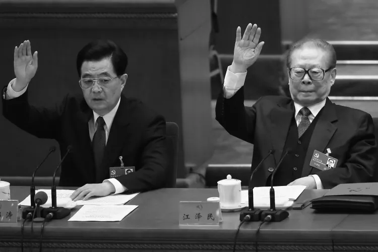 Former Chinese Communist Party head Hu Jintao and former Party head Jiang Zemin raise their hands during the closing session of the 18th Party Congress on Nov. 14, 2012, in Beijing. Hu visited Yancheng City, Jiangsu to deal with a Falun Gong matter in December, according to a source. (Feng Li/Getty Images)