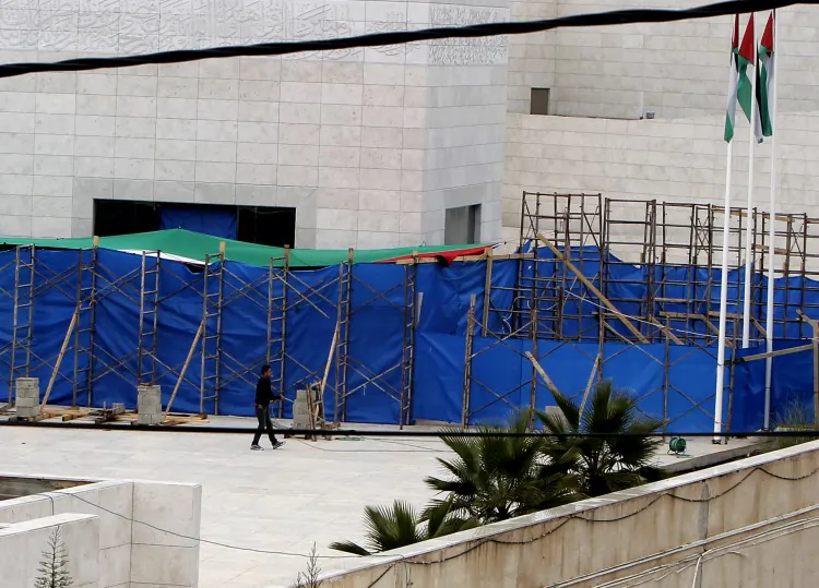 A Palestinian worker walks with a water hose in front of the tarpaulin hiding the mausoleum of the late Palestinian leader Yasser Arafat, on Nov. 27, at the Muqataa in the West Bank city of Ramallah. (Ahmad Gharabli/AFP/Getty Images)