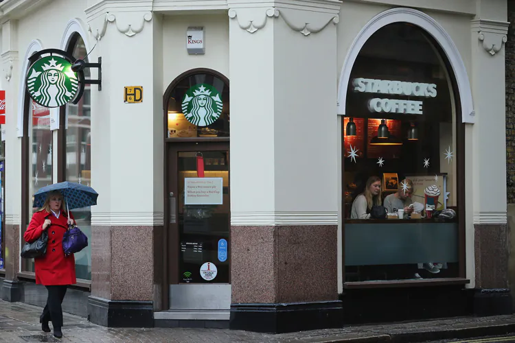 A woman passes by the door of a Starbucks coffee shop in London, Dec. 3. Starbucks Corp. this week announced plans to open 3,000 new stores by 2017. (Dan Kitwood/Getty Images)