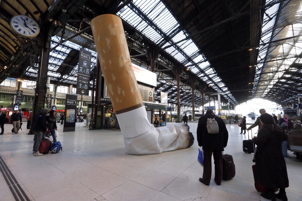 People pass by a giant mock-up discarded cigarette displayed on the ground at the Gare de Lyon railway station in Paris, on Dec. 4, 2012, as part of a public-awareness campaign. (Pierre Verdy/AFP/Getty Images)