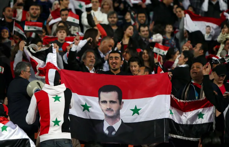 A Syrian man waves his national flag bearing the image of embattled President Bashar al-Assad during his country's team match against Iraq in the 7th West Asia Football Federation (WAFF) championship in Kuwait City on December 13, 2012. (Marwan Naamani/AFP/Getty Images)