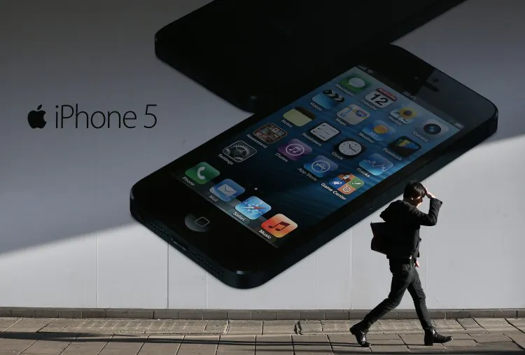 A shopper walks past a giant advertisement for the Apple iPhone 5 near Oxford Street on Dec. 17, 2012 in London. Hedge fund manager David Einhorn argues that Apple should do more to unlock shareholder value. (Peter Macdiarmid/Getty Images)