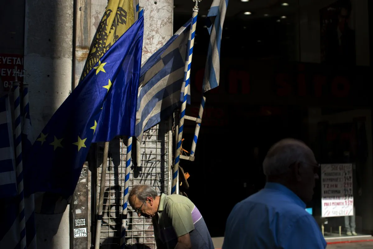 People walk past a shop selling Greek and European Union flags in central Athens, Thursday, July 16, 2015. (AP Photo/Emilio Morenatti)