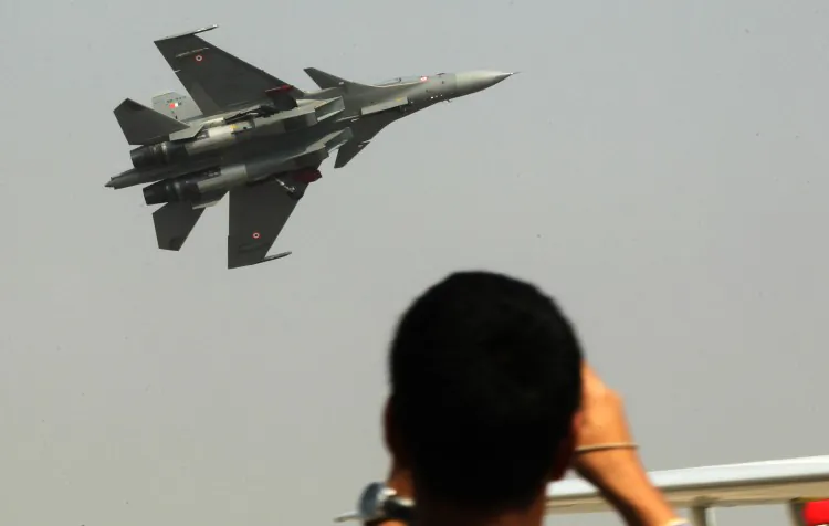 Visitors watch a fighter jet perform during the second day of the Aero India Show 2013 in Bangalore on February 7, 2013. (STR/AFP/Getty Images)