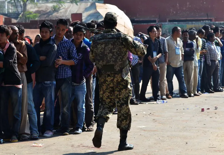 An Indian security officer walks past Naga tribal voters standing in queue at a polling station in Dimapur in the northeastern state of Nagaland on February 23, 2013. (STRDEL/AFP/Getty Images)