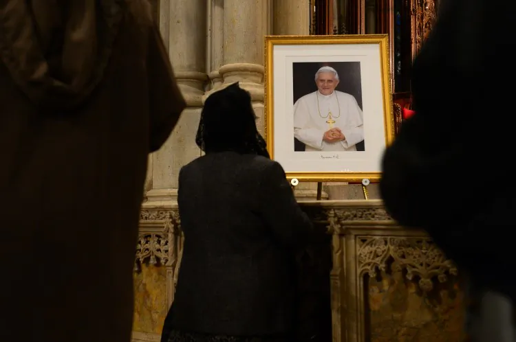 A woman kneels in front of a portrait of Pope Benedict XVI after mass was held in celebration of the Pope at St. Patrick's Cathedral in New York, Feb. 28, 2013. (Emmanuel Dunad/AFP/Getty Images)